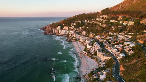 Clifton-beachfront-hotels-overlooking-turquoise-ocean-at-sunset-in-Cape-Town,-aerial