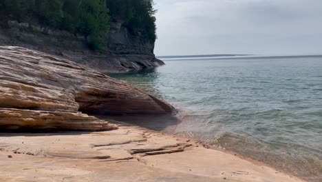 Waves-Rolling-Over-Large-Rock-Formations-on-Lake-Superior-with-Trees-and-Cliffs-Coastline-Pictured-Rocks-National-Lakeshore