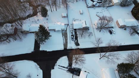 Aerial-view-of-a-beautiful-Winter-landscape-with-bare-trees-colorful-small-houses-in-snow,-roads,-forest-and-streets