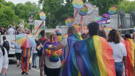 Pride-marchers-wave-rainbow-banners-and-flags-from-behind-in-slow-motion
