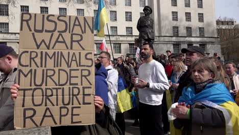 A-person-holds-a-placard-that-reads,-“Russian-war-criminals-murder-torture-rape”-on-a-protest-against-the-Russian-war-on-Ukraine