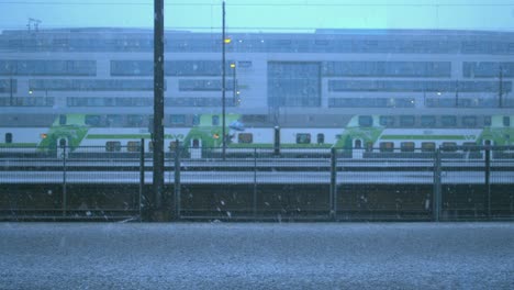 Modern-train-rolls-slowly-through-station-platform-on-snowy-winter-day