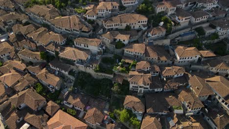 Charming-Ottoman-houses-cascade-down-valley,-stone-and-alabaster-city-of-Berat,-Albania,-High-angle-aerial-view