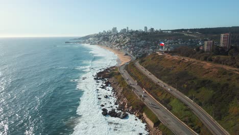Aerial-view-passing-above-Avenida-BorgoÃ±o-coastline-traffic-ReÃ±aca-cityscape-sunny-beach-waterfront