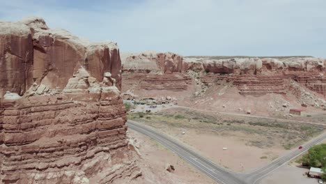 Buttes-De-Arenisca-Y-Formaciones-Rocosas-Rojas-Por-Carretera-Desértica-En-El-Suroeste-Del-Desierto-De-Utah---Aéreo