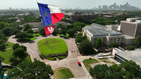Las-Banderas-De-La-Universidad-De-Houston-Y-Texas-Ondean-Sobre-El-Campus-Con-El-Horizonte-Del-Centro-A-La-Vista-El-Día-De-Verano