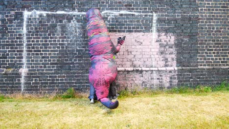 Funny-dancing-prehistoric-dinosaur-costume-as-bubbles-float-against-brick-wall