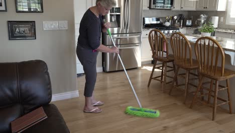 Senior-woman-dusts-and-sweeps-her-kitchen-floors---tilt-up