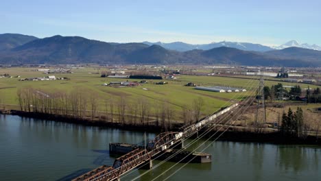 Tranquil-Scene-With-Rail-Bridge-Crossing-A-River-In-Mission,-British-Columbia,-Canada---aerial-drone-shot