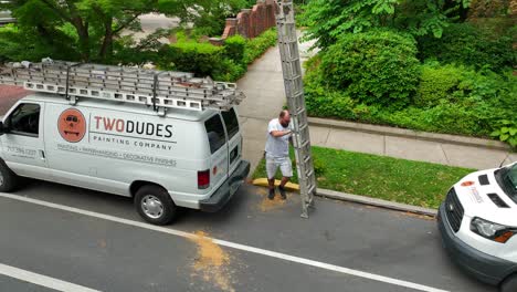 Blue-collar-worker-unloads-ladder-from-company-van-to-begin-painting-project