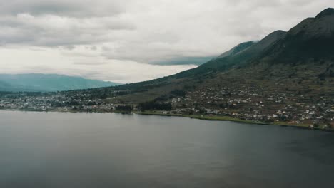 Laguna-De-San-Pablo-Y-Ciudad-En-La-Ladera-Con-Alturas-Crecientes-Del-Volcán-Imbabura-En-Otavalo,-Ecuador