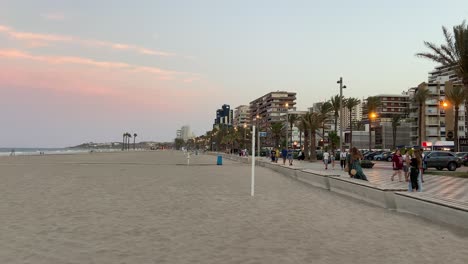 Menschen,-Die-Bei-Einem-Wunderschönen-Sonnenuntergang-Entlang-Der-Promenade-Von-San-Juan-De-Alicante-Neben-Dem-Strand-Spazieren
