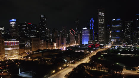 Die-Boom-Aufnahme-Aus-Der-Luft-Zeigt,-Dass-Die-Skyline-Von-Chicago-Nachts-Blau-Und-Rot-Erleuchtet-Ist