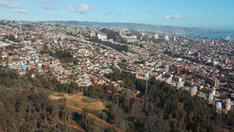 Aerial-pan-right-of-ViÃ±a-del-Mar-city-buildings-panormic-view-from-hill,-mountains-and-sea-in-background,-Chile