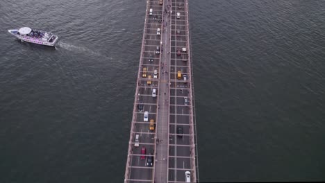 Aerial-view-above-the-busy-Brooklyn-bridge,-revealing-Manhattan-skyline,-dusk-in-NYC,-USA---tilt,-drone-shot