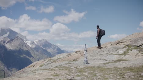 Black-male-traveler-with-backpack-thinking-about-GOD-and-crossing-himself-while-looking-up-mountainside-near-the-Matterhorn-in-Switzerland