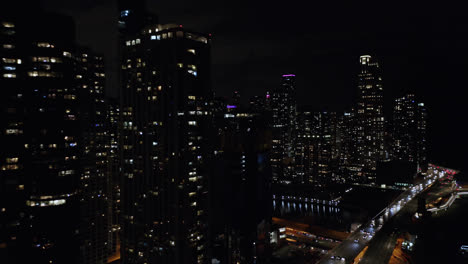 Beautiful-aerial-drone-shot-along-the-many-high-rise-office-and-residential-buildings-along-the-Chicago-River-in-Chicago,USA-at-night-time
