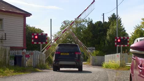 Vehicle-waiting-at-level-crossing-as-the-safety-barriers-lift-as-a-train-has-passed