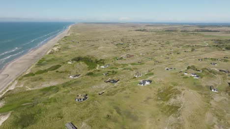 An-aerial-view-Small-houses-stand-between-high-and-grassy-sand-dunes
