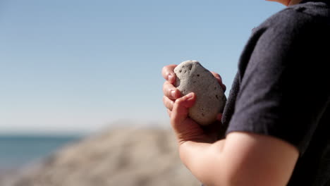 Boy-holding-a-rock-by-the-water