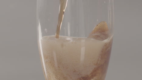 Tilt-up-of-Cola-being-poured-in-glass-foaming-and-rising-to-surface---240-fps-slow-motion