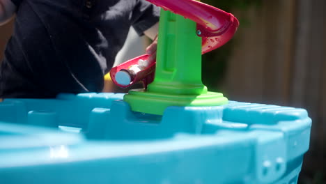 Kind-Schiebt-Seine-Spielsachen-Eine-Spielzeugwasserrutsche-Hinunter