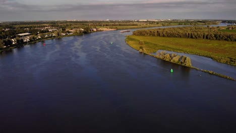 Aerial-View-Of-FPS-Waal-Cargo-Container-Vessel-Manoeuvring-On-River-Bend-On-Oude-Maas-In-The-Distance