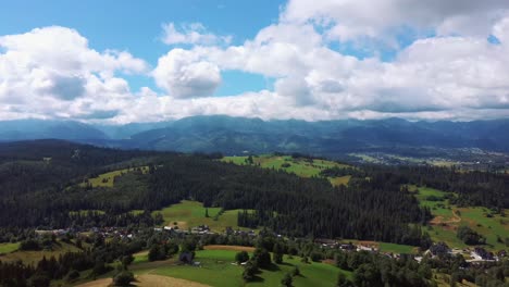 Luftaufnahme-In-Epischen-Berggipfeln-Eines-Alpendorfes,-Mit-Kiefern-Im-Dunst-Bedeckte-Hügel,-Sonnenaufgangslicht