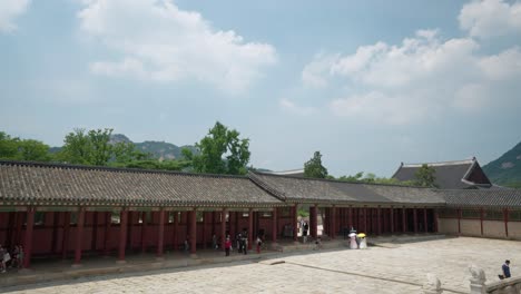 Tourists-enter-Geunjeongjeon-square-Hall-through-Geunjeongmun-gate-on-a-summer-day-in-Seoul,-Gyeongbokgung-Palace
