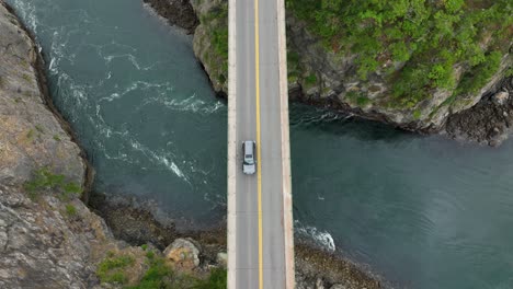 Overhead-shot-of-cars-driving-over-a-bridge-with-water-passing-underneath