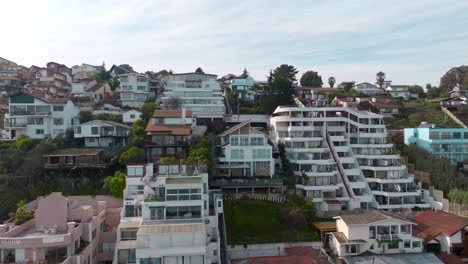 Aerial-truck-right-of-luxury-houses-and-apartments-in-hillside-near-the-sea-in-sector-5-of-ReÃ±aca,-Valparaiso,-Chile