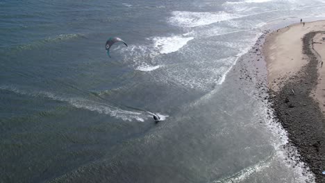 Skilled-windsurfer-along-the-coast-of-California-on-a-windy-day---aerial-follow-view