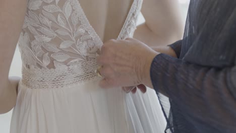 Mother-zipping-up-the-back-of-Bride's-wedding-dress