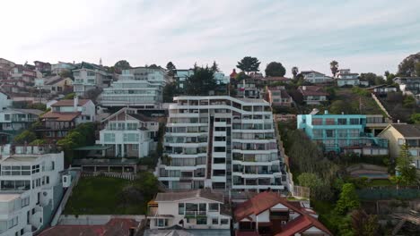 Aerial-truck-right-of-luxury-apartments-and-houses-in-hillside-near-the-shore-in-sector-5-of-ReÃ±aca,-ViÃ±a-del-Mar,-Chile
