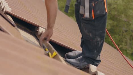 Closeup-of-worker-using-crowbar-to-remove-roof-tiles-for-solar-panel,-day