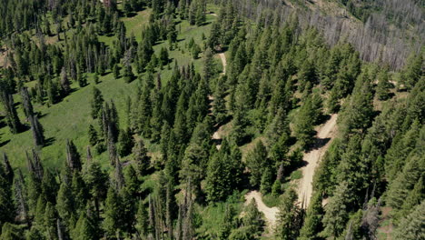 Aerial-following-winding-alpine-road-across-ridge-in-green-mountains