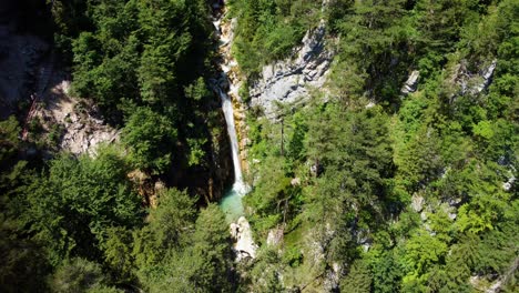 Stable-aerial-shot-of-an-abandoned-waterfall-in-the-middle-of-a-forest-and-rocky-surroundings