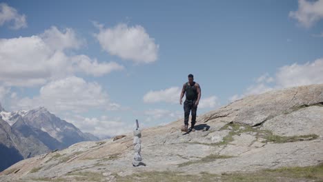 Black-male-traveler-with-backpack-getting-up-and-walking-along-scenic-mountainside-near-the-Matterhorn-in-Switzerland