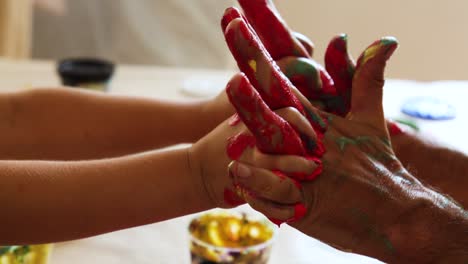 Intertwined-hands-and-fingers-of-child-and-adult-with-red-paint-on-them-for-connection-and-cooperation-concept