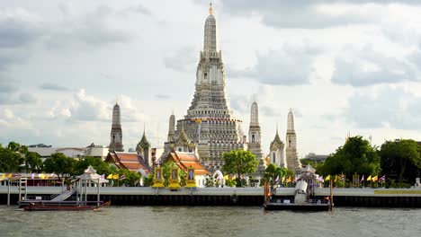 Aufnahme-Des-Wunderschönen-Wat-Arun-Tempels-In-Bangkok,-Thailand,-Mit-Blick-Auf-Vorbeifahrende-Motorboote-Mit-Touristen-Am-Abend