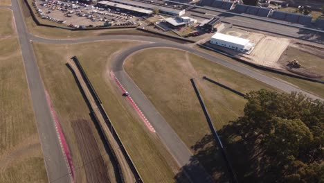 Aerial-drone-tilt-down-view-of-white-classic-vintage-race-car-driving-on-Buenos-Aires-racetrack-circuit