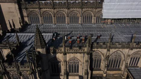 Aerial-drone-flight-alonside-Manchester-Cathedral-showing-off-its-Gothic-architecture-and-bee-hives-on-the-rooftop