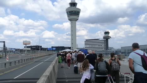 Schlange-Von-Menschen,-Die-In-Der-Nähe-Von-Kontrolltürmen-Auf-Der-Start--Und-Landebahn-Des-Amsterdamer-Flughafens-Schiphol-Zum-Einsteigen-Gehen