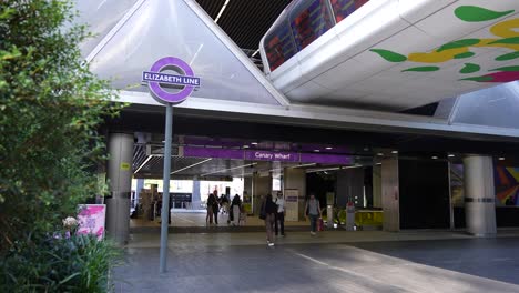 Canary-Wharf,-London,-United-Kingdom---August-2022---A-few-people-are-walking-in-and-out-of-the-new-station-to-the-Elizabeth-Line-in-Canary-Wharf-during-a-sunny-summer-morning
