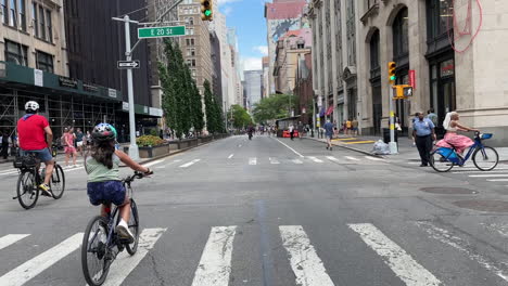 Tilt-Down-From-Blue-Sky-To-People-Riding-Bikes-On-Closed-Street-In-Manhattan,-New-York-City,-U