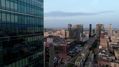 Aerial-View-of-Warsaw,-Poland,-Flying-by-Skyscraper-Windows,-Modern-Skyscraper-and-Prosta-Avenue-Traffic,-Drone-Shot