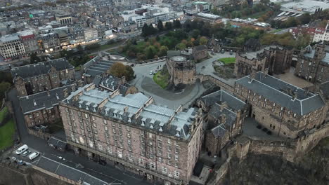 Eine-Beeindruckende-Drohnenaufnahme-Mit-Blick-Auf-Edinburgh-Castle-Und-Einem-Schwenk-Nach-Oben,-Um-Arthurs-Sitz-In-Der-Ferne-Bei-Sonnenuntergang-Zu-Sehen