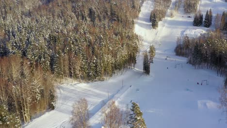 drone-shot-of-reveling-snowy-ski-slope-surrounded-by-forests-in-Estonia