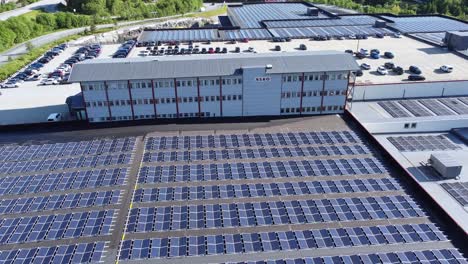 Huge-solar-powerplant-in-front-of-Asko-company-building-with-logo-in-Arna-outside-Bergen,-Norway---Aerial-view-looking-down-at-industrial-warehouse-supplied-by-clean-renewable-energy