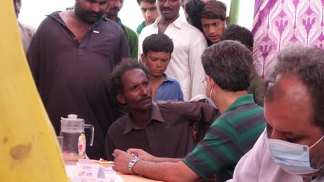 Trabajador-Humanitario-Ayudando-Y-Escuchando-A-Los-Lugareños-Durante-El-Campamento-De-Socorro-Contra-Inundaciones-En-Sindh,-Pakistán